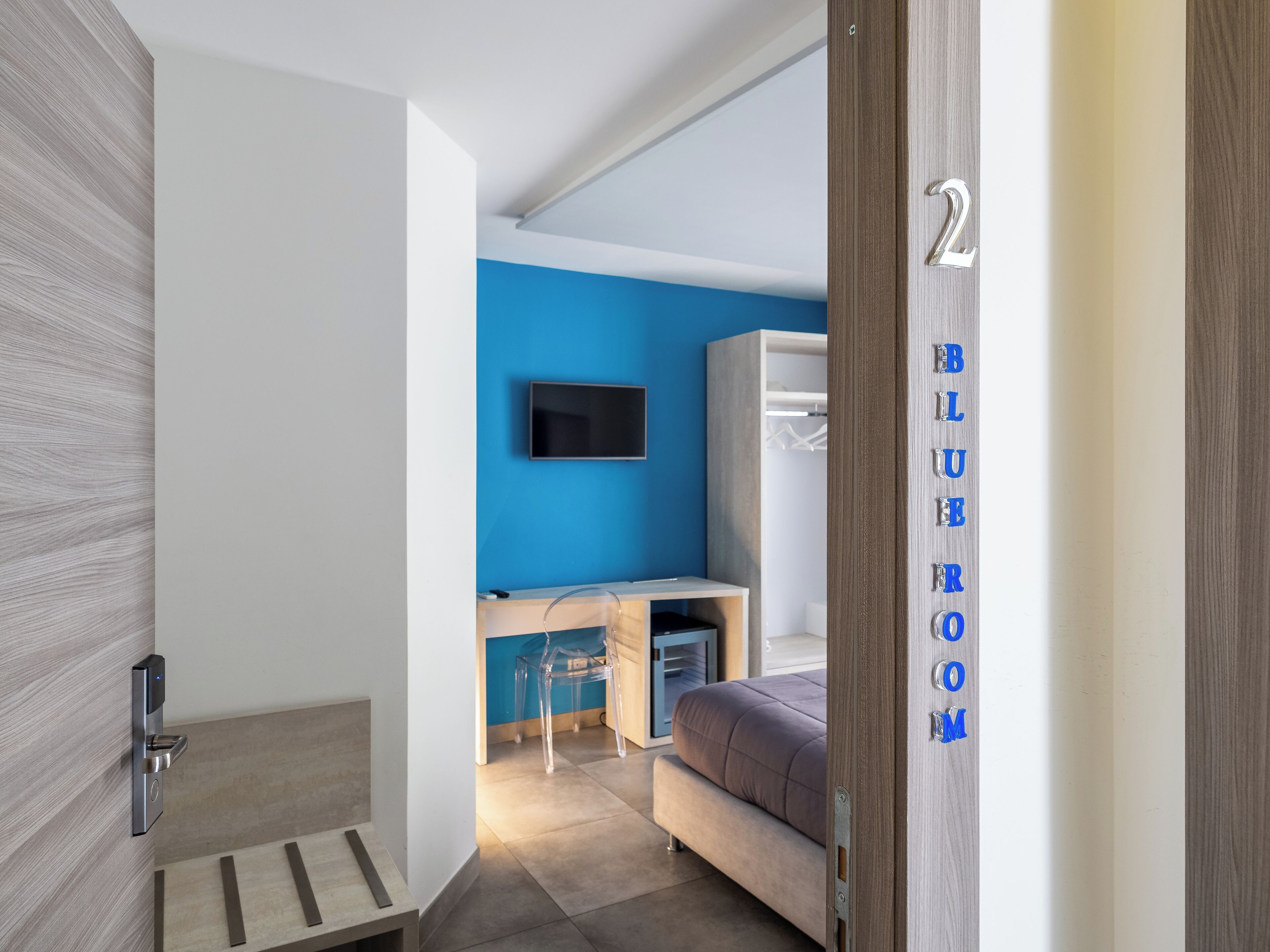 Quarto moderno com uma cama, uma escrivaninha e uma televisão.
