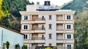 Un hôtel à plusieurs étages, doté de balcons et d’une enseigne indiquant qu’il s’agit de l’hôtel Rokusu-Rou.