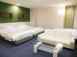 A hotel room with two beds, a white sofa, a glass coffee table, and green wall art. - Hotel Rokusui-Rou (Ito)