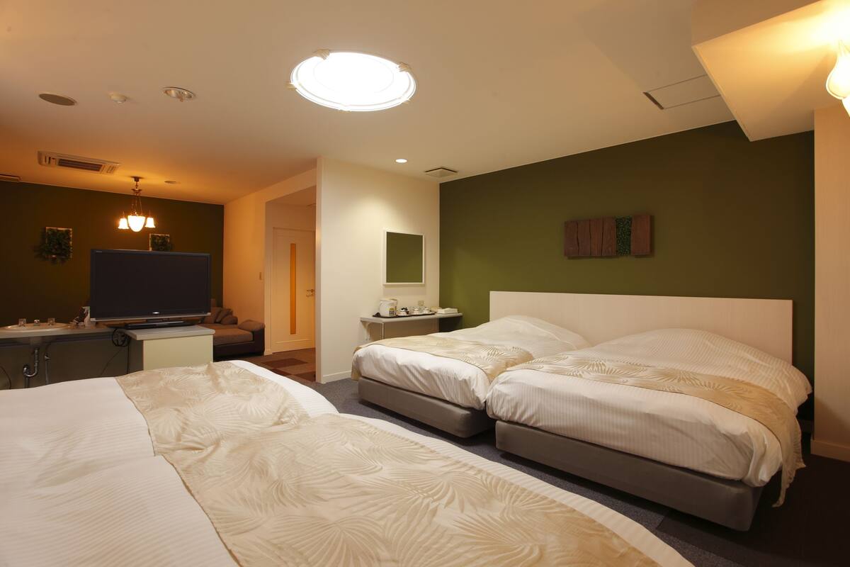 Habitación de hotel con dos camas, televisión, escritorio y una mesita.