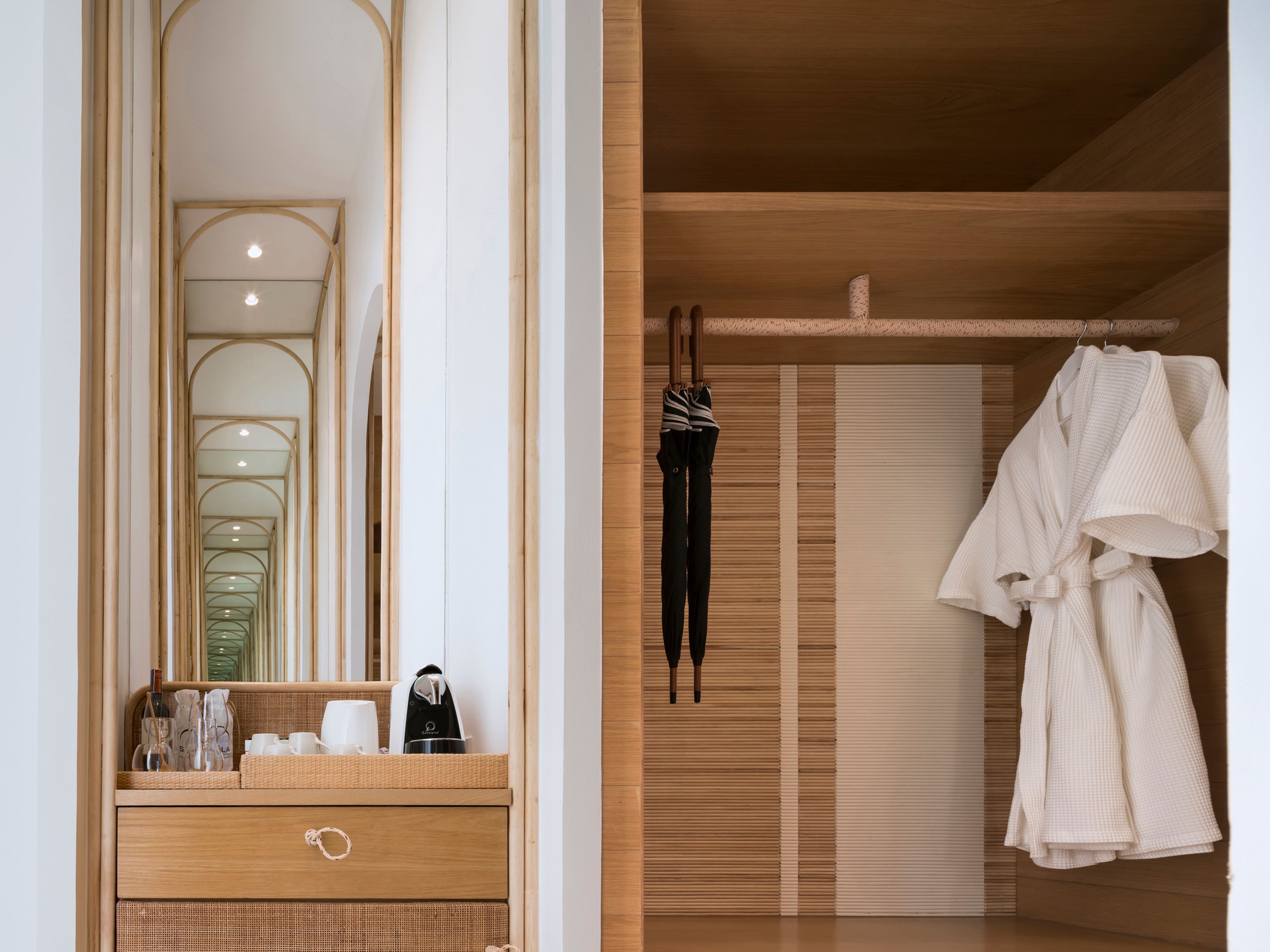 Een badkamer met een houten wastafelmeubel, een spiegel en een handdoekrek met badjassen.