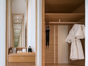 Un baño con tocador de madera, espejo y perchero con batas.