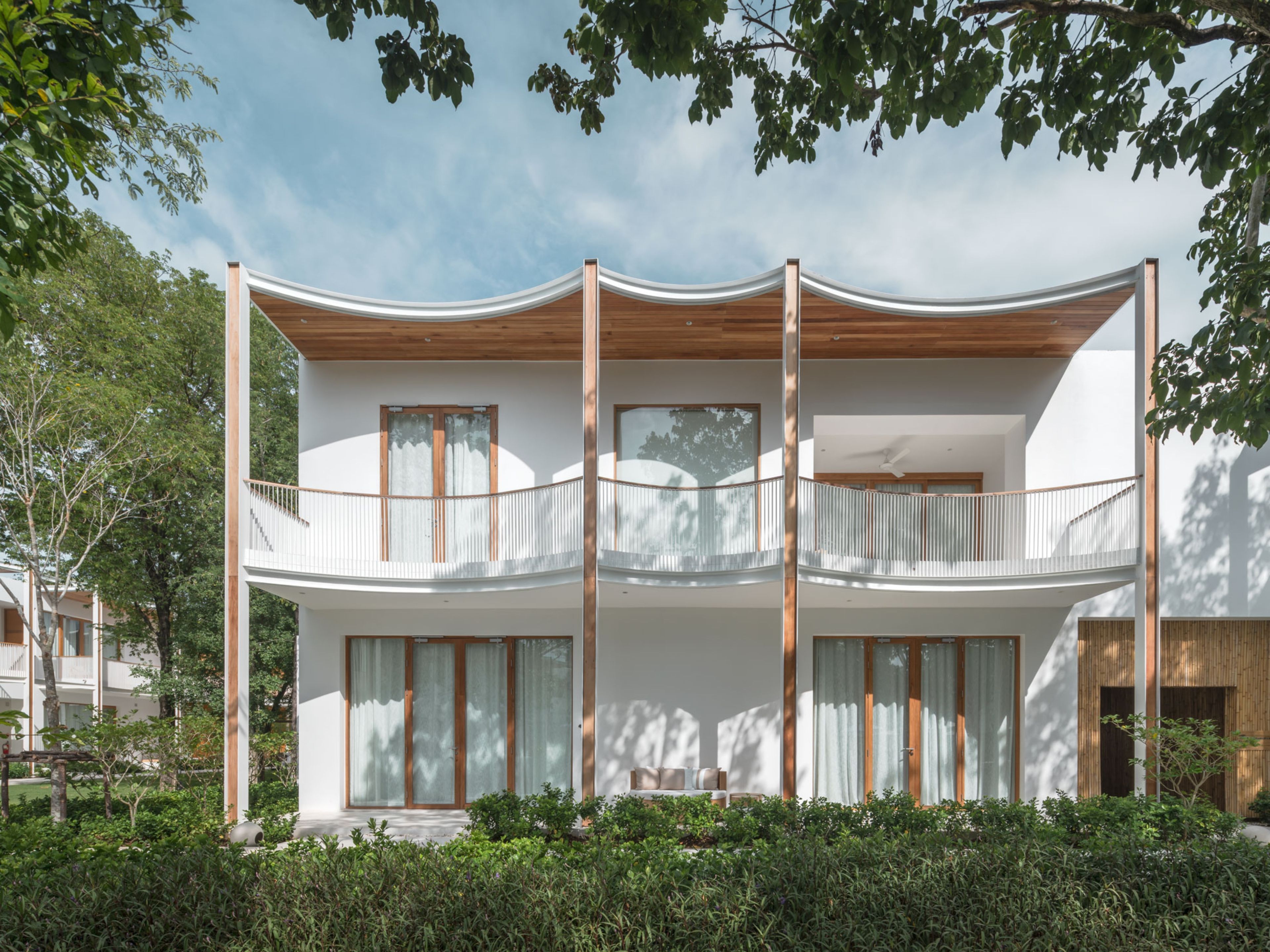 Un edificio moderno a due piani con un balcone, ampie finestre e un soffitto in legno.