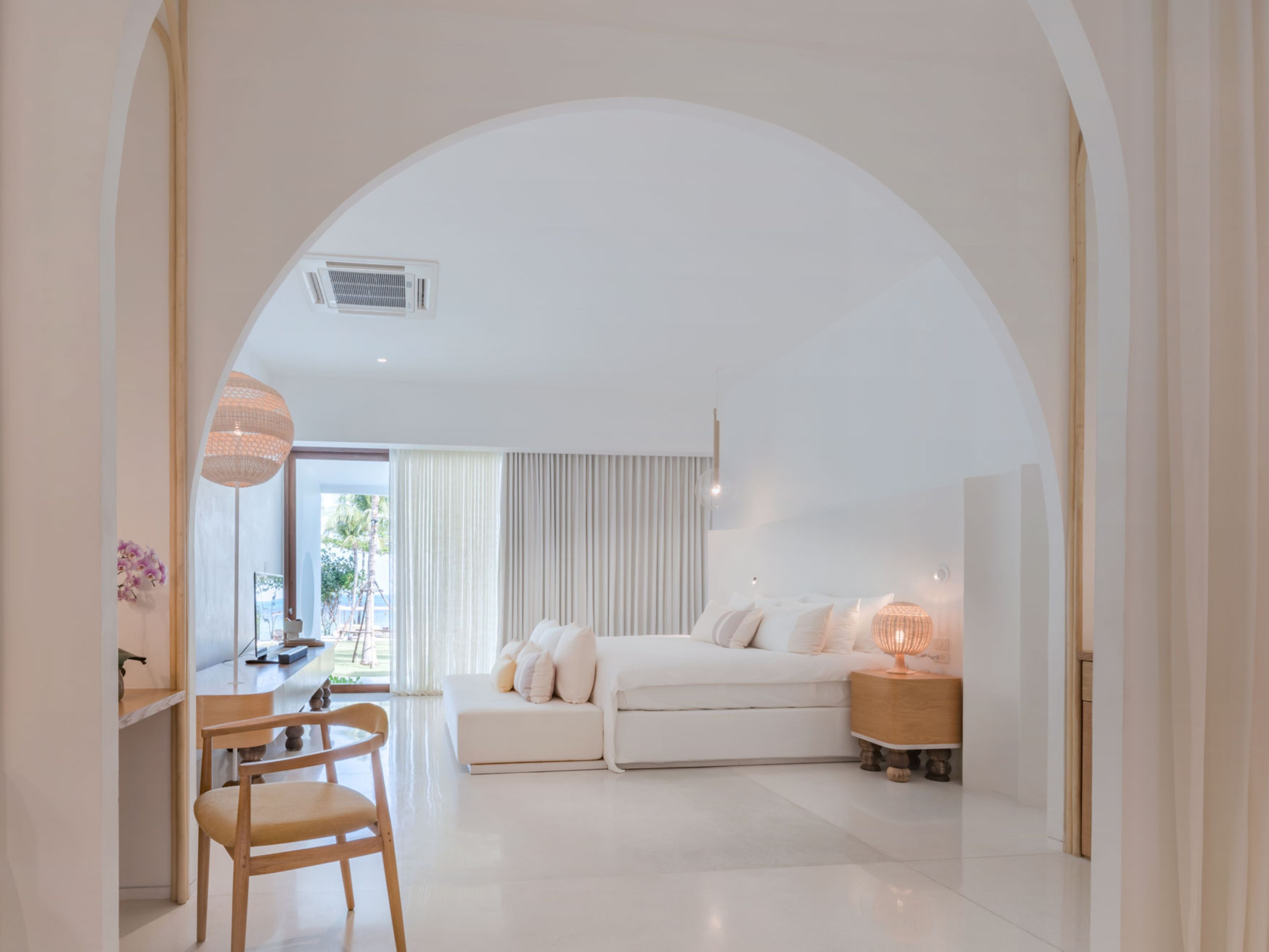 Un dormitorio moderno con una cama grande, mesitas de noche y un escritorio con una silla.
