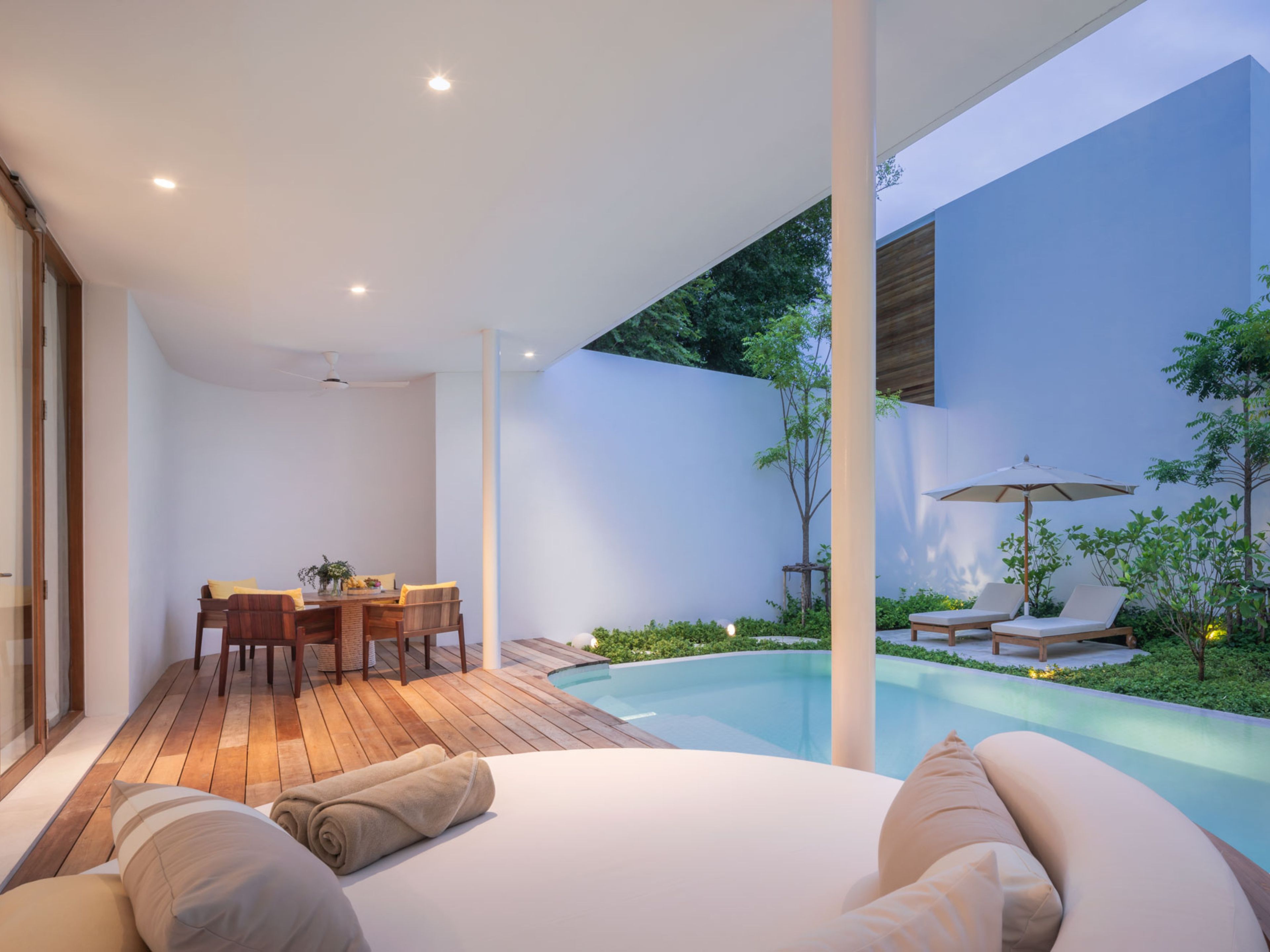 Un espacio exterior moderno con piscina, zona de comedor y asientos tipo lounge.