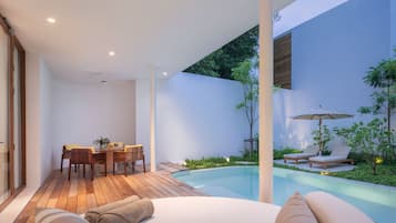 Un espacio exterior moderno con piscina, zona de comedor y asientos tipo lounge.