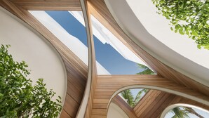 A modern architectural design with curved wooden beams and white walls, featuring a skylight and a view of palm trees. - SALA Samui Chaweng Beach Resort (Koh Samui)