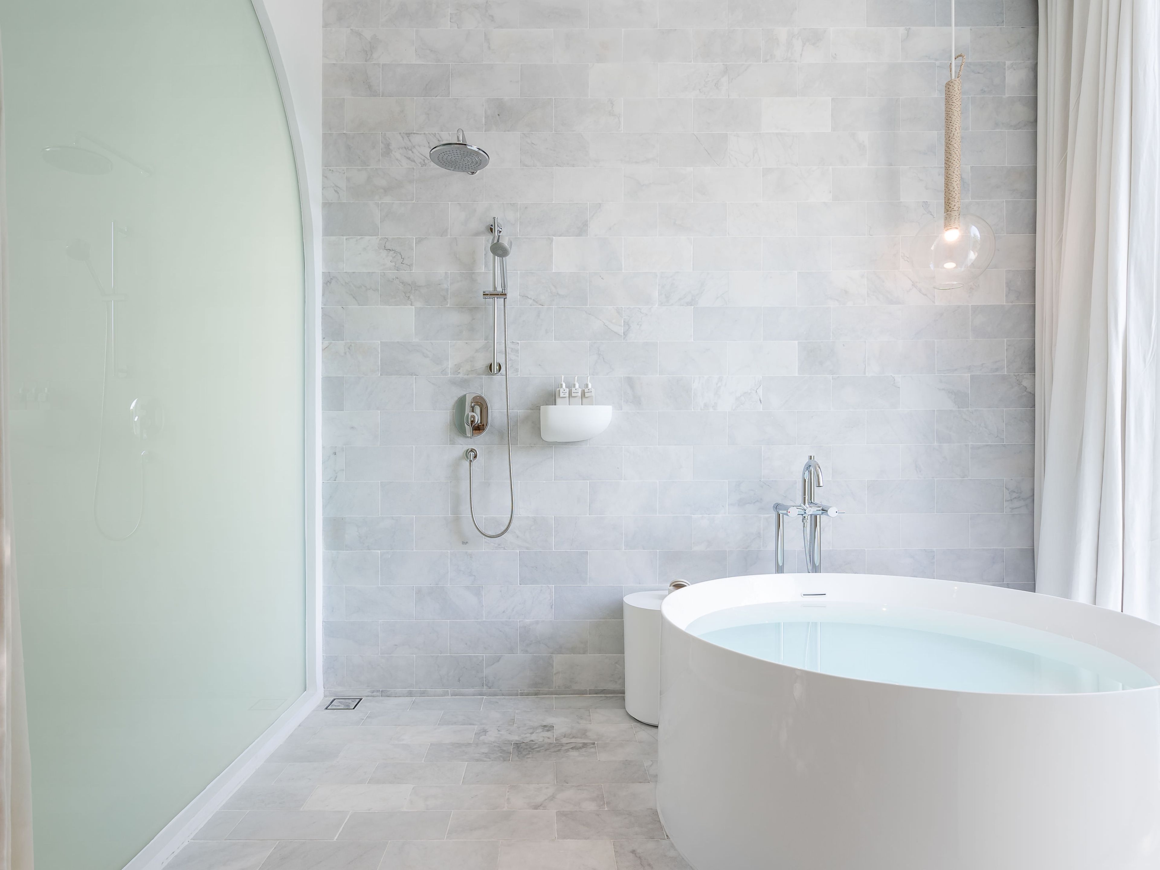 A modern bathroom with a freestanding bathtub, a showerhead, and a wall-mounted sink.