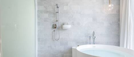 A modern bathroom with a freestanding bathtub, a showerhead, and a wall-mounted sink.