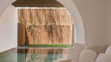Un área de spa con pared de madera, una piscina pequeña y un sofá blanco con toallas.
