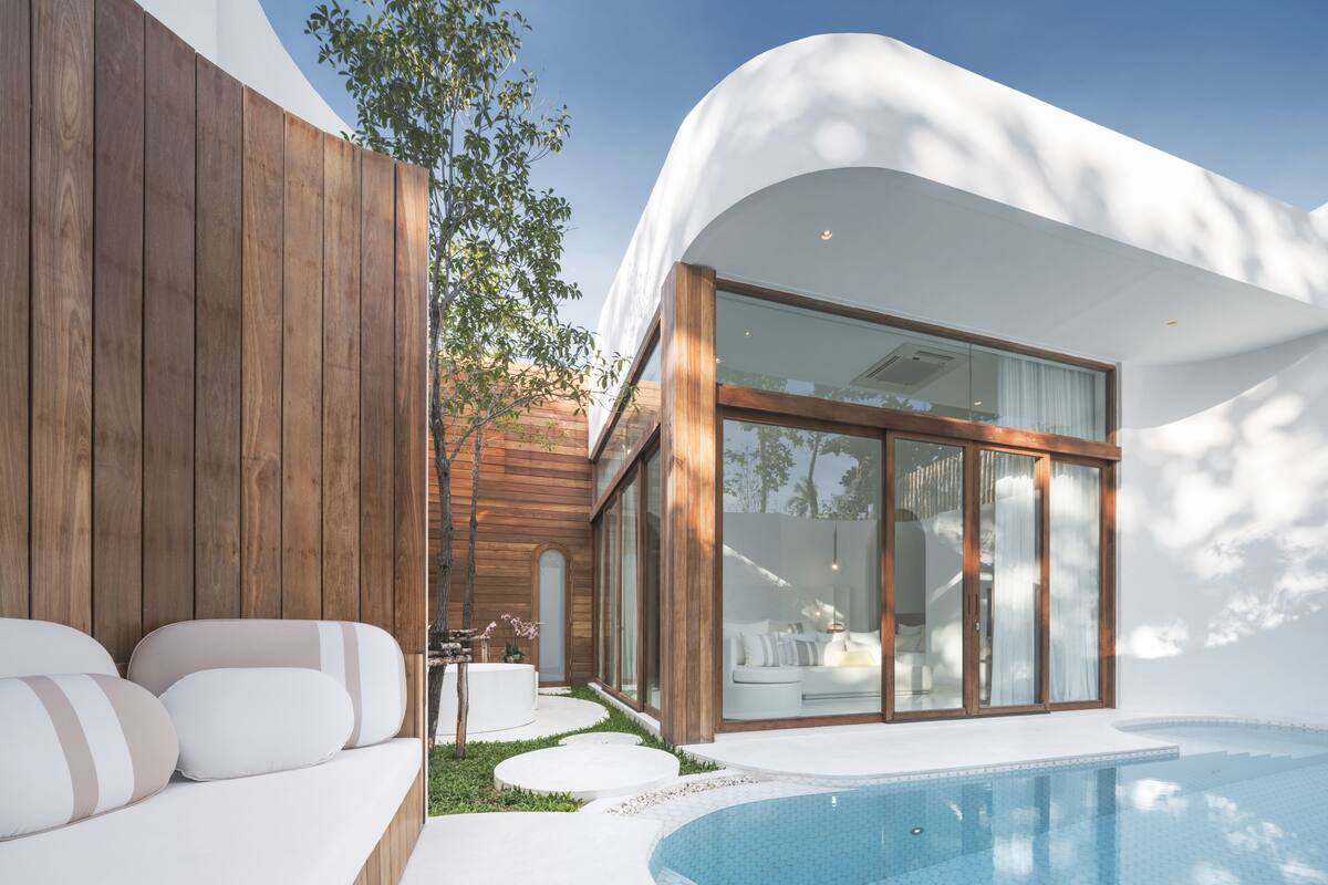 Une maison moderne dotée d’une piscine, d’une façade en bois et d’une porte vitrée donnant sur un espace de vie.