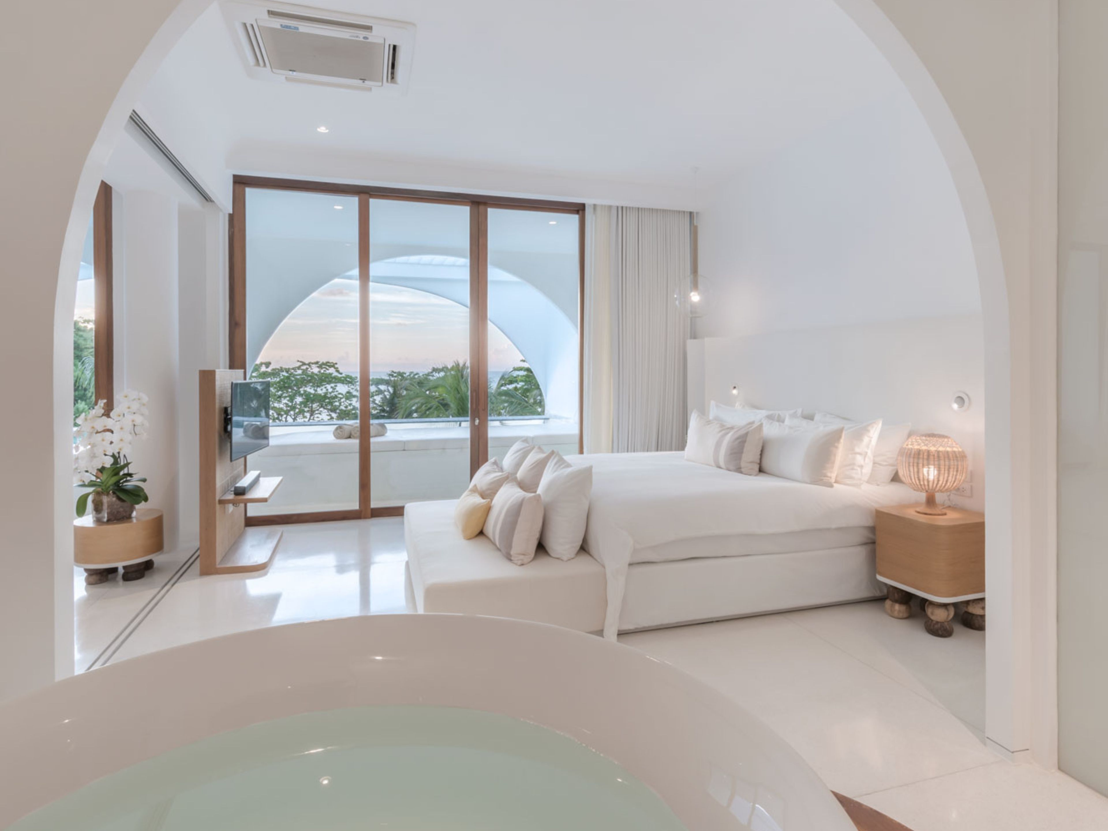 Un dormitorio moderno con una cama grande, televisor y bañera.