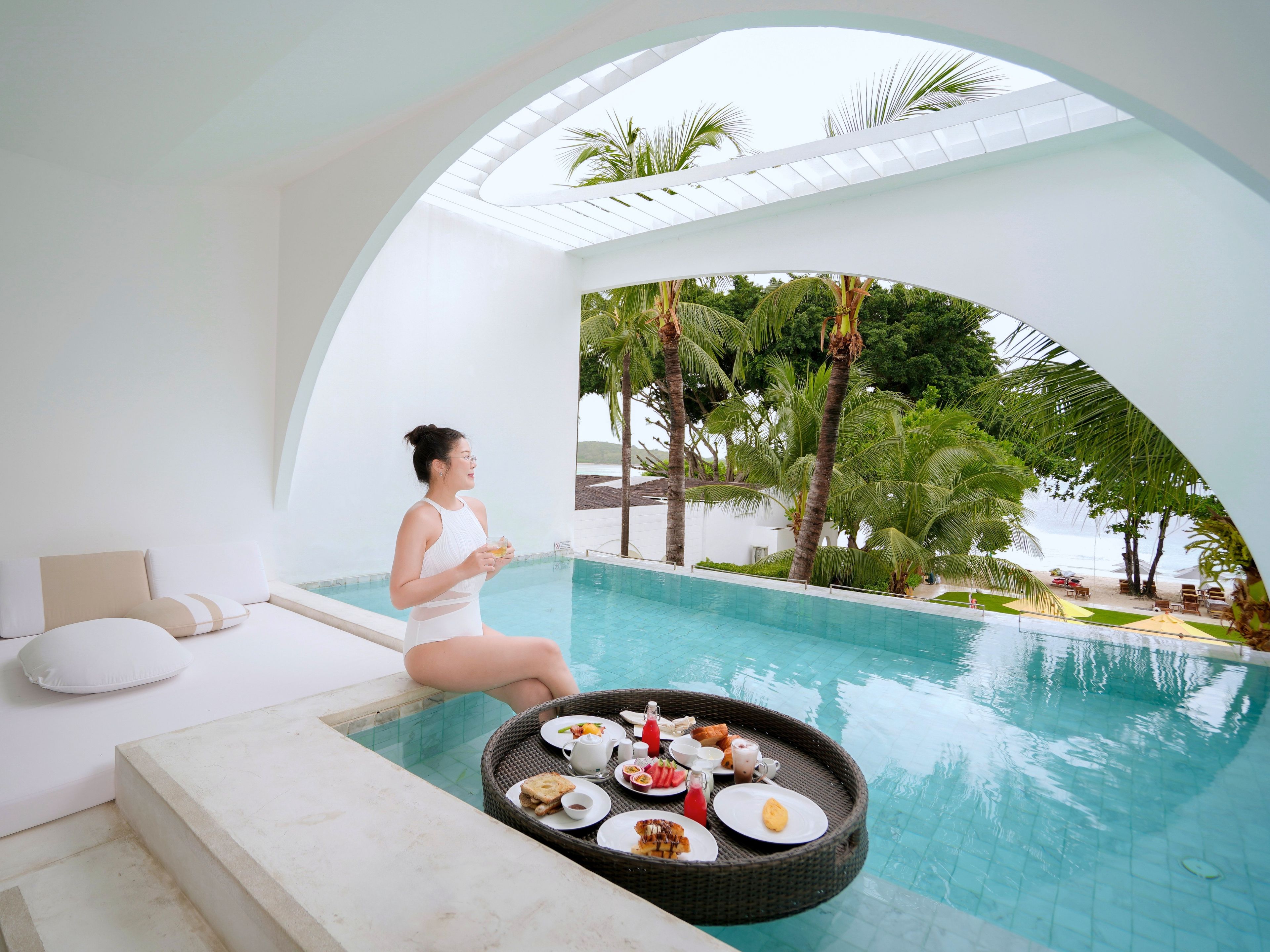 Zona de piscina con mobiliario de comedor y una persona relajándose junto a la piscina.