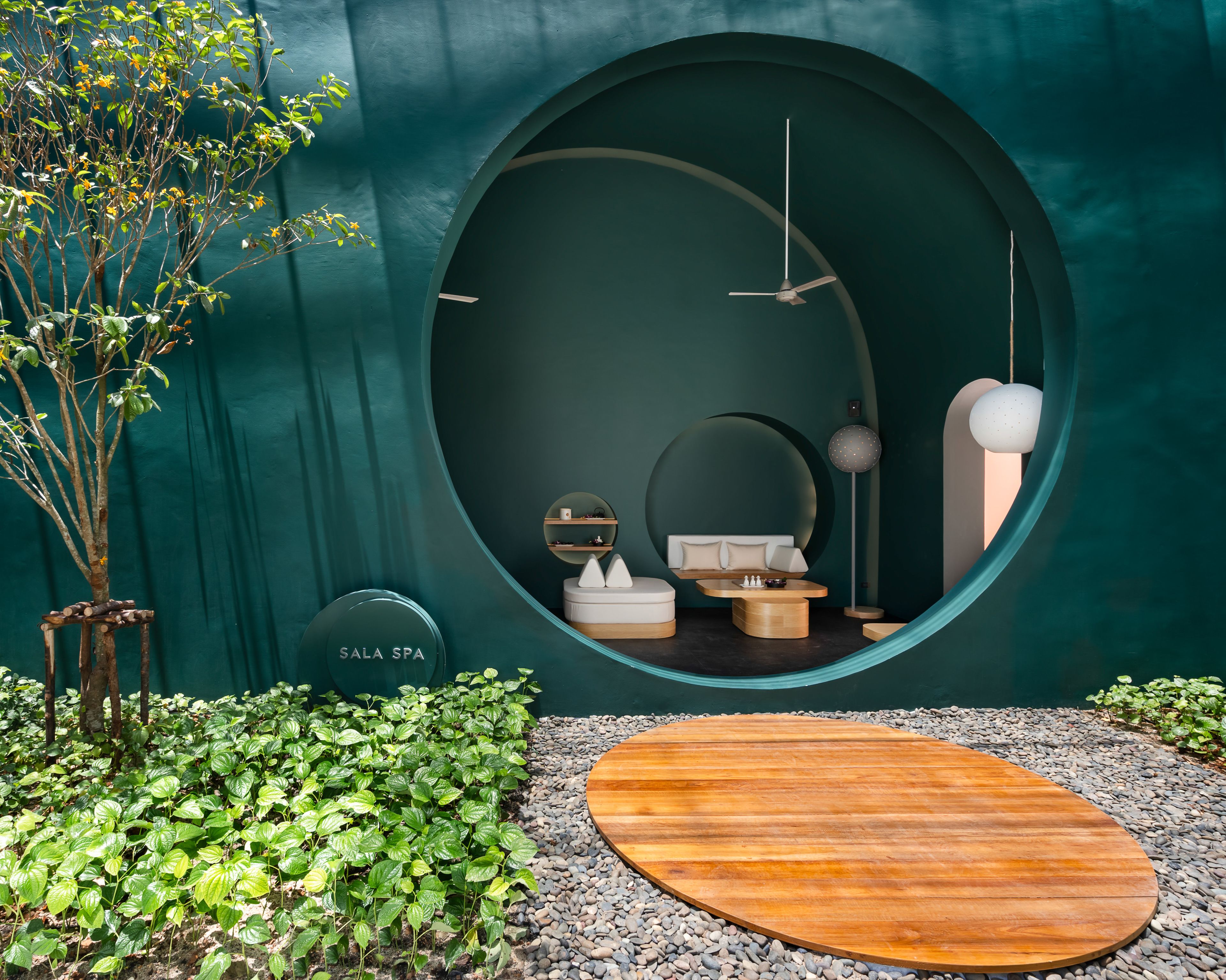 A spa room with a circular window, a wooden bench, and a small table with a chess set.