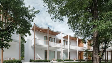 Een modern, meerlaags gebouw met een gebogen gevel, balkons en een verzorgd gazon.