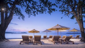 A beach with lounge chairs and umbrellas, a clear sky, and a calm sea. - SALA Samui Chaweng Beach Resort (Koh Samui)