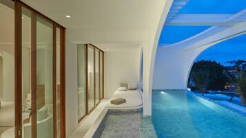 Relax in a spacious living area with a fireplace and enjoy a balcony overlooking a serene pool area.