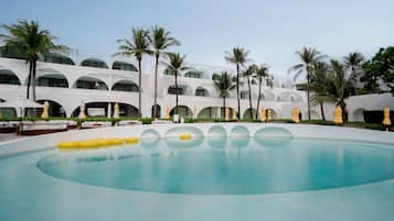 A hotel with a large pool, palm trees, and white architecture.
