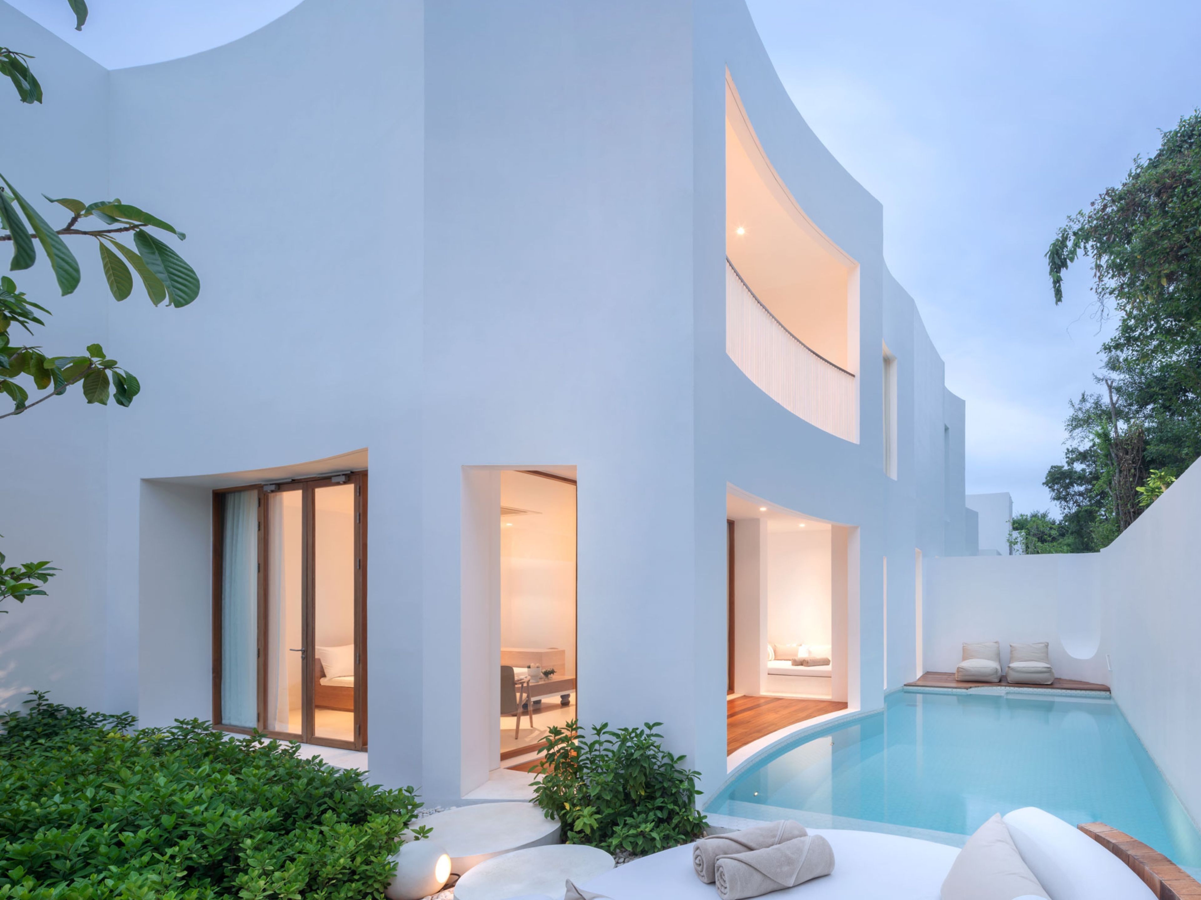 A modern house with a swimming pool, multiple entryways, and a well-maintained garden.