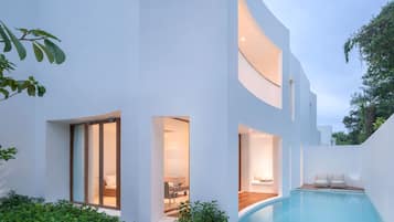A modern house with a swimming pool, multiple entryways, and a well-maintained garden.