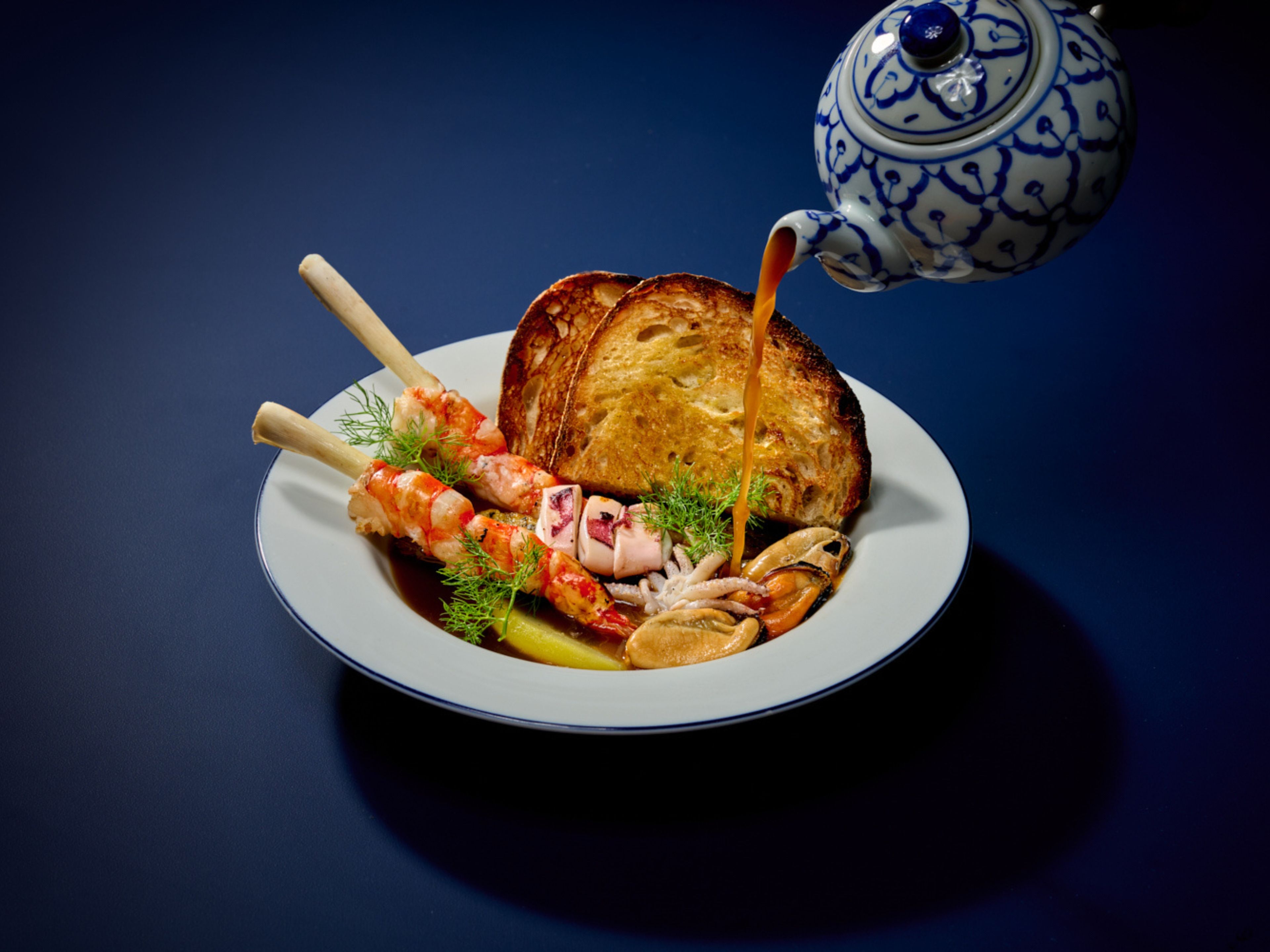 Un piatto con frutti di mare, pane e un teiera.