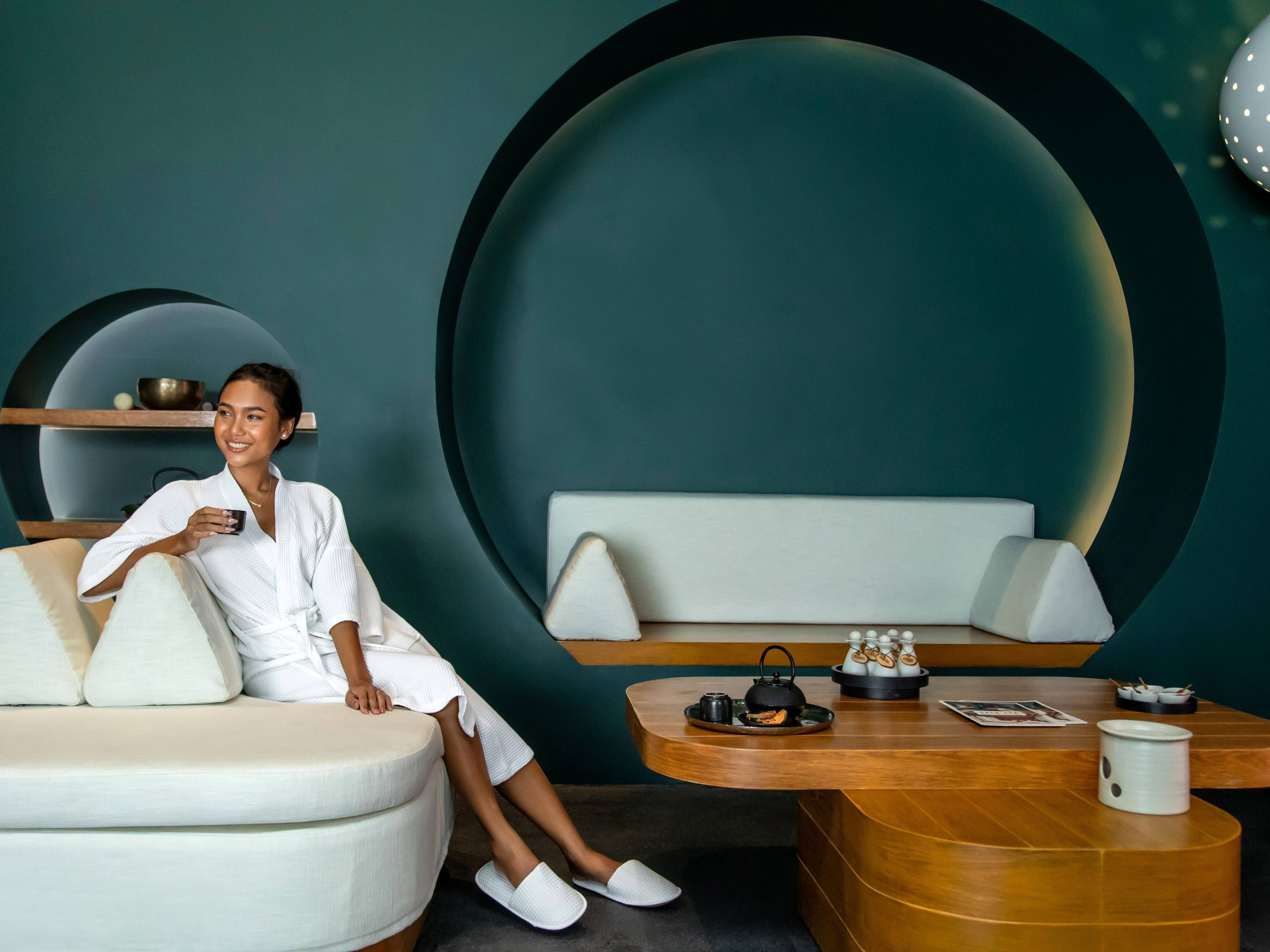 A modern interior with a seating area, a table with tea set, and a decorative bowl on a shelf.