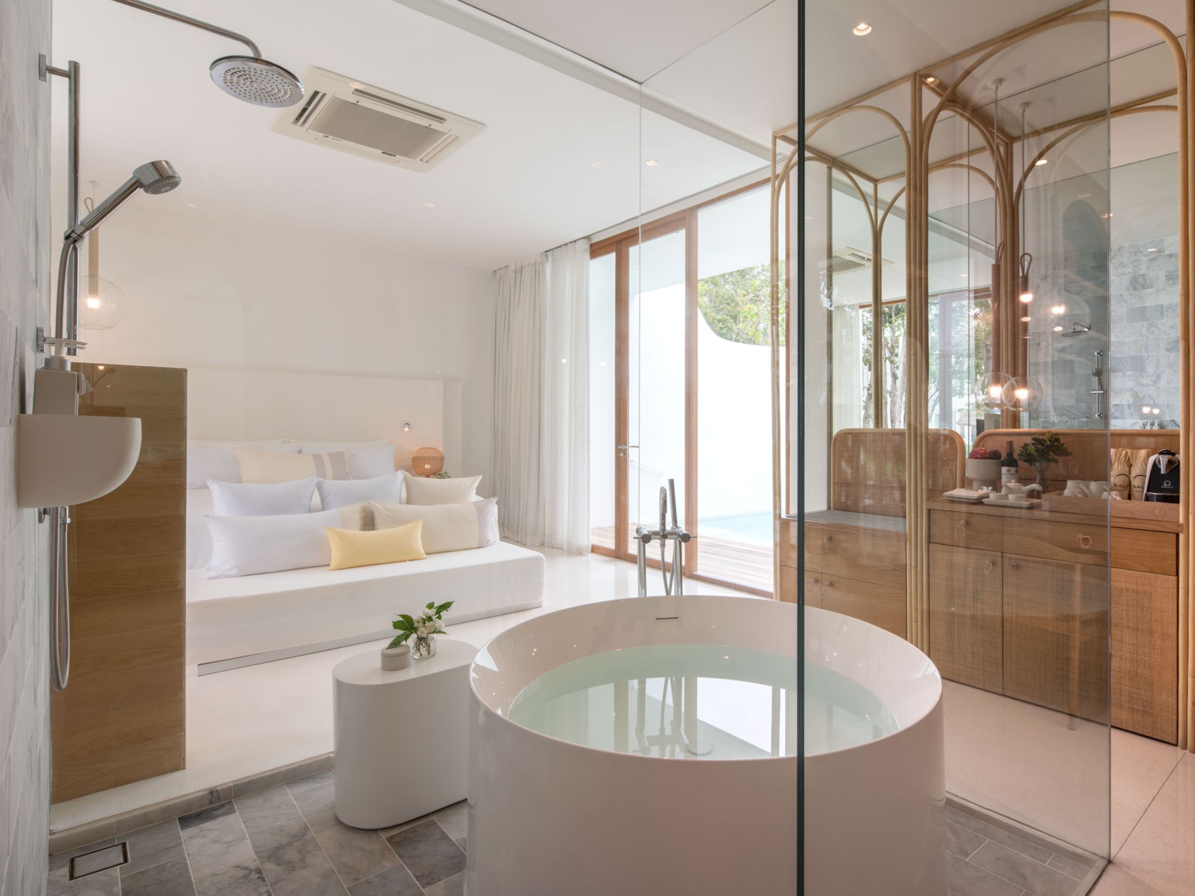 Un baño moderno con una bañera grande, zona de ducha y un área de descanso con sofá y una mesita.