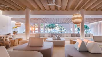 Un salon moderne doté d’un ventilateur de plafond, de sièges confortables et de grandes fenêtres donnant sur une plage.