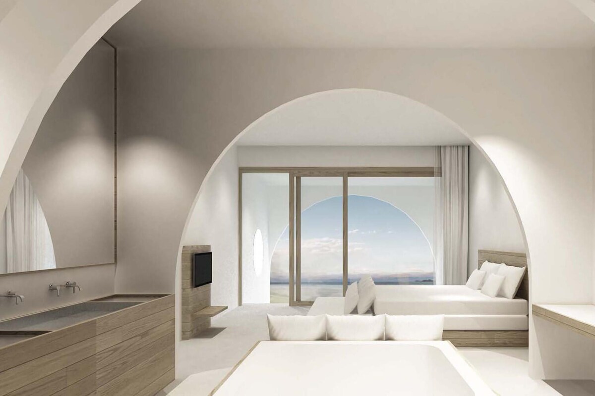 A modern bedroom with a large bed, a TV, and a bathroom with a sink and mirror.