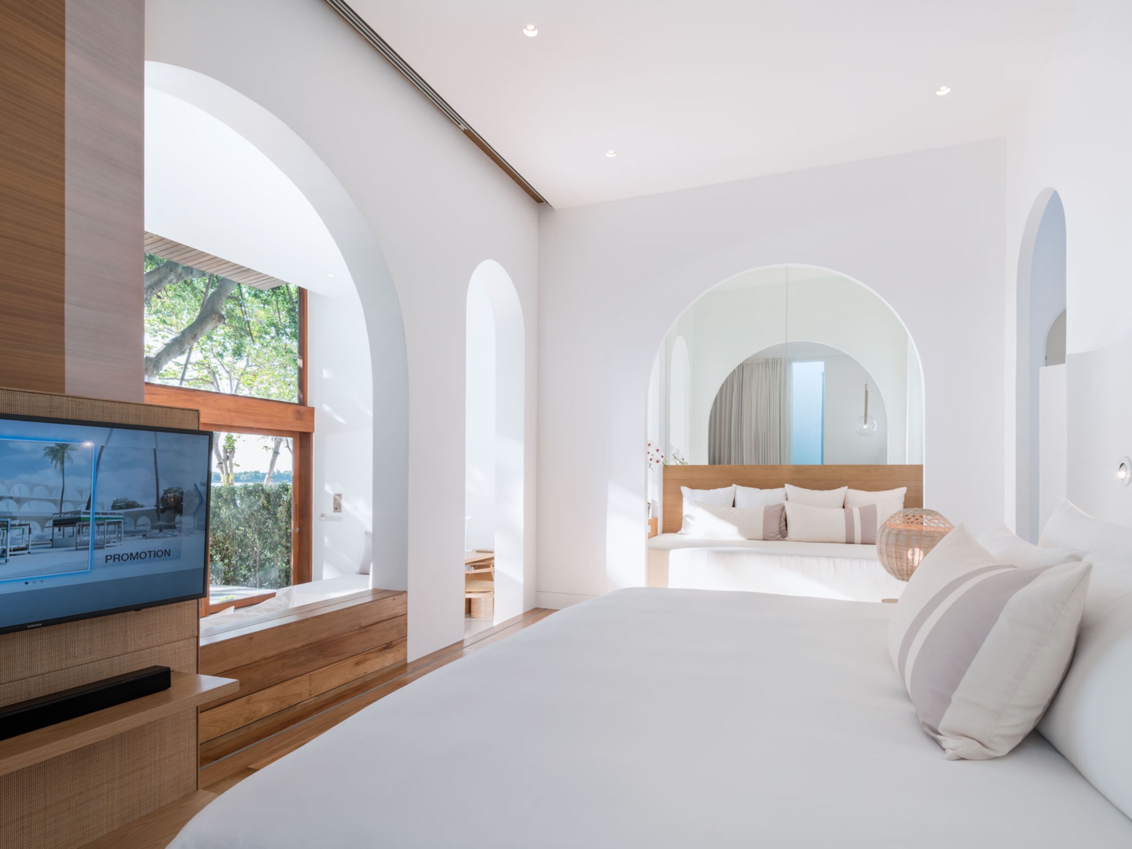 A modern hotel room with a large bed, a television, and a view of the outdoors.