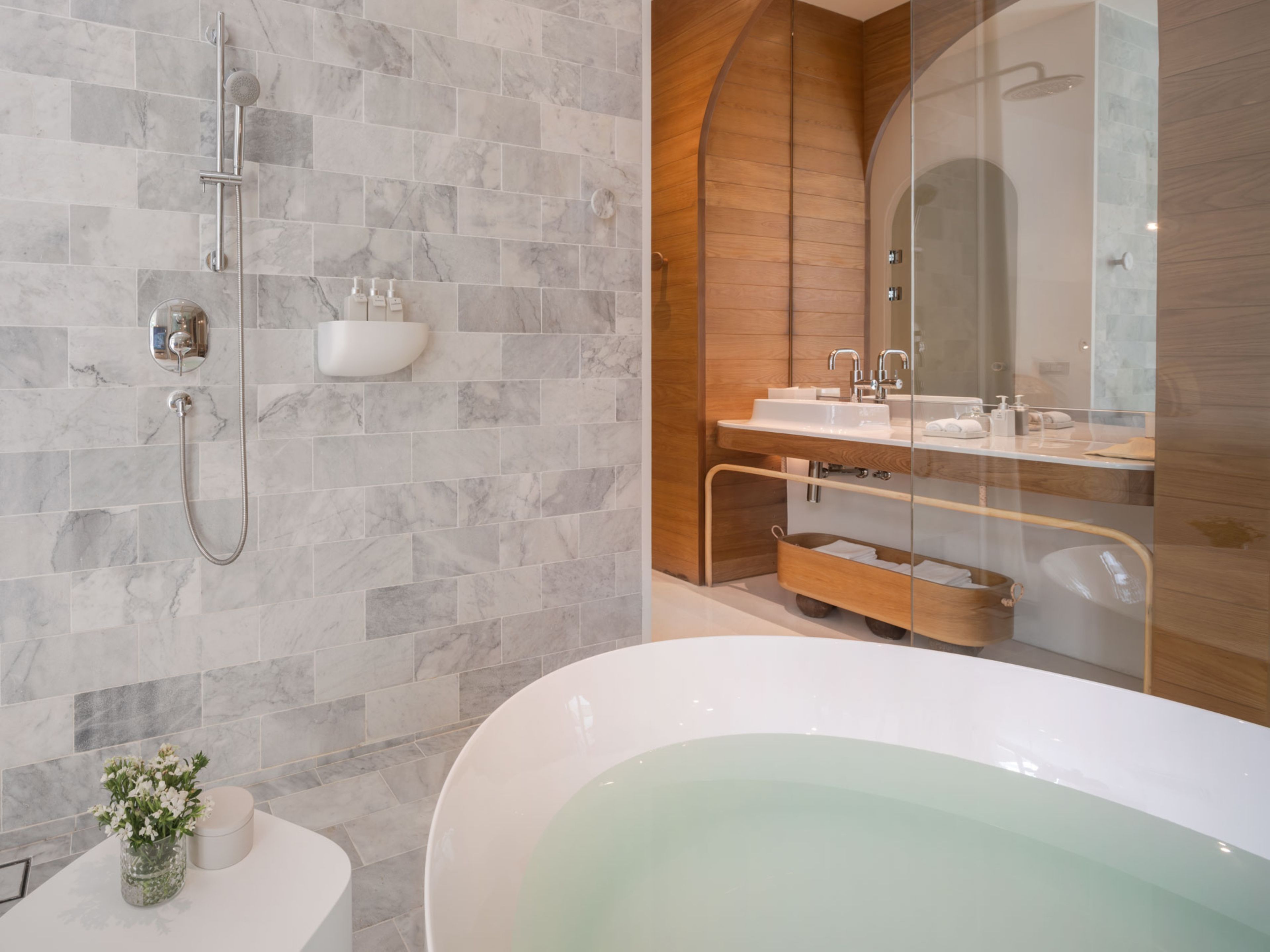 A modern bathroom with a freestanding bathtub, a glass-enclosed shower, and a vanity with a mirror.