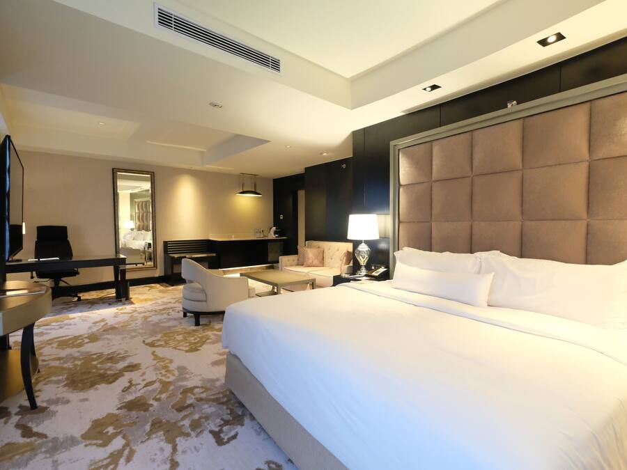 A hotel room with a large bed, a desk, a chair, a TV, and a bathroom.