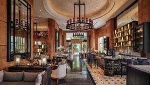 A spacious lobby with a bar area, seating, and a chandelier.