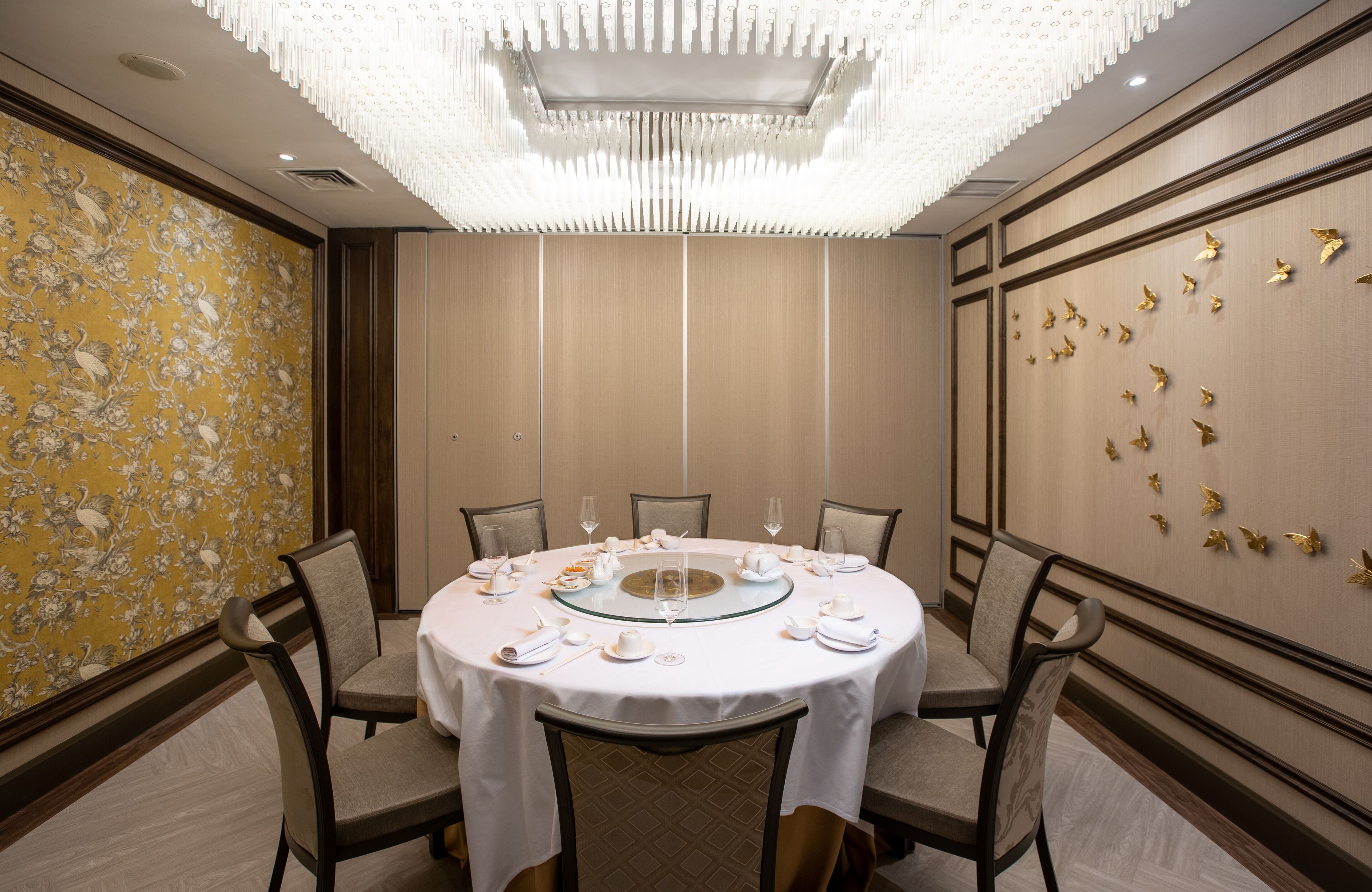 Un salón de conferencias con una mesa redonda, sillas y una pared decorativa con detalles dorados.