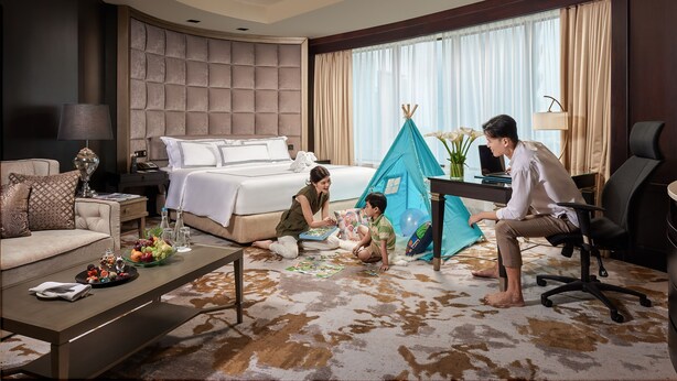 A hotel room with a bed, a desk, a chair, a sofa, a coffee table, and a tent.