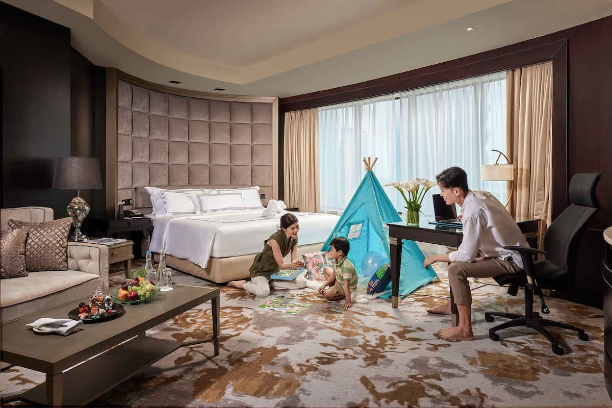 A hotel room with a bed, a desk, a chair, a sofa, a coffee table, and a tent.