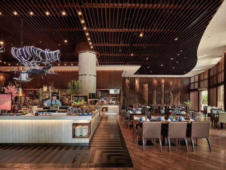 Un restaurante moderno con un mostrador central, techo de madera y zona de comedor con mesas y sillas.