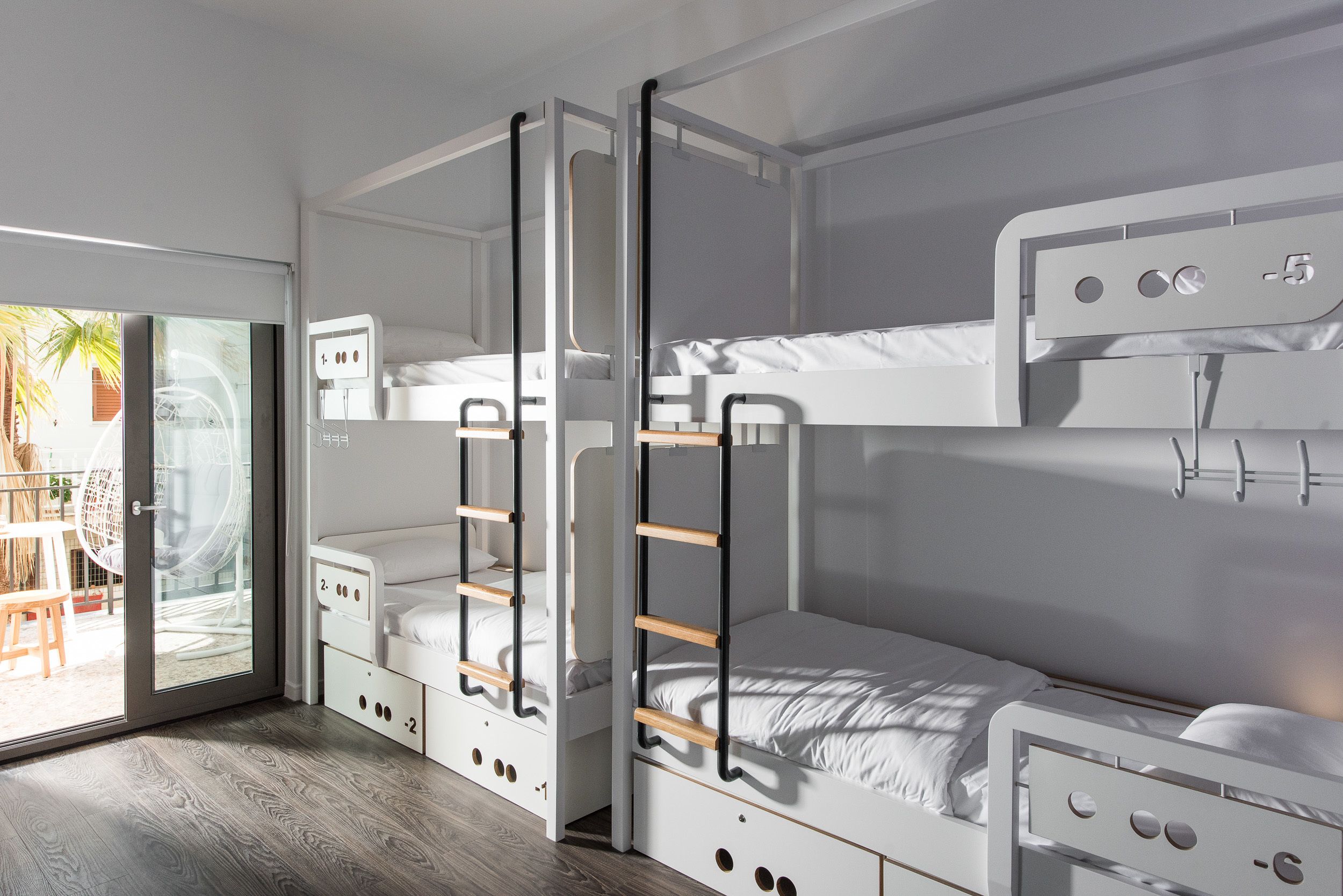 A modern room with bunk beds, a sliding glass door to a patio, and a small table with chairs.