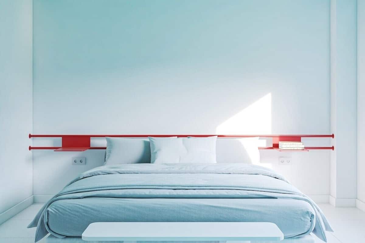 Ein modernes Schlafzimmer mit Bett, weißen Wänden und einem roten Kopfteil.