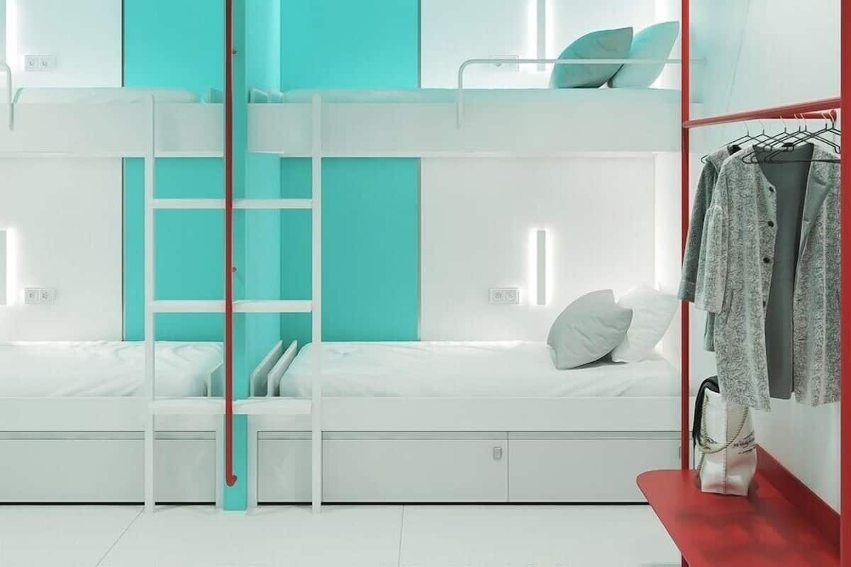 Ein modernes Schlafzimmer mit Etagenbetten, einer roten Bank und einem Kleiderständer.