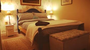 Una camera da letto con un letto, lampade da comodino, un comodino, un tappeto e un quadro appeso alla parete.