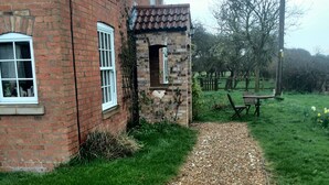 A brick house with a gravel path leading to a wooden bench and a table. - Brampton Dales Farm B&B (Gainsborough)