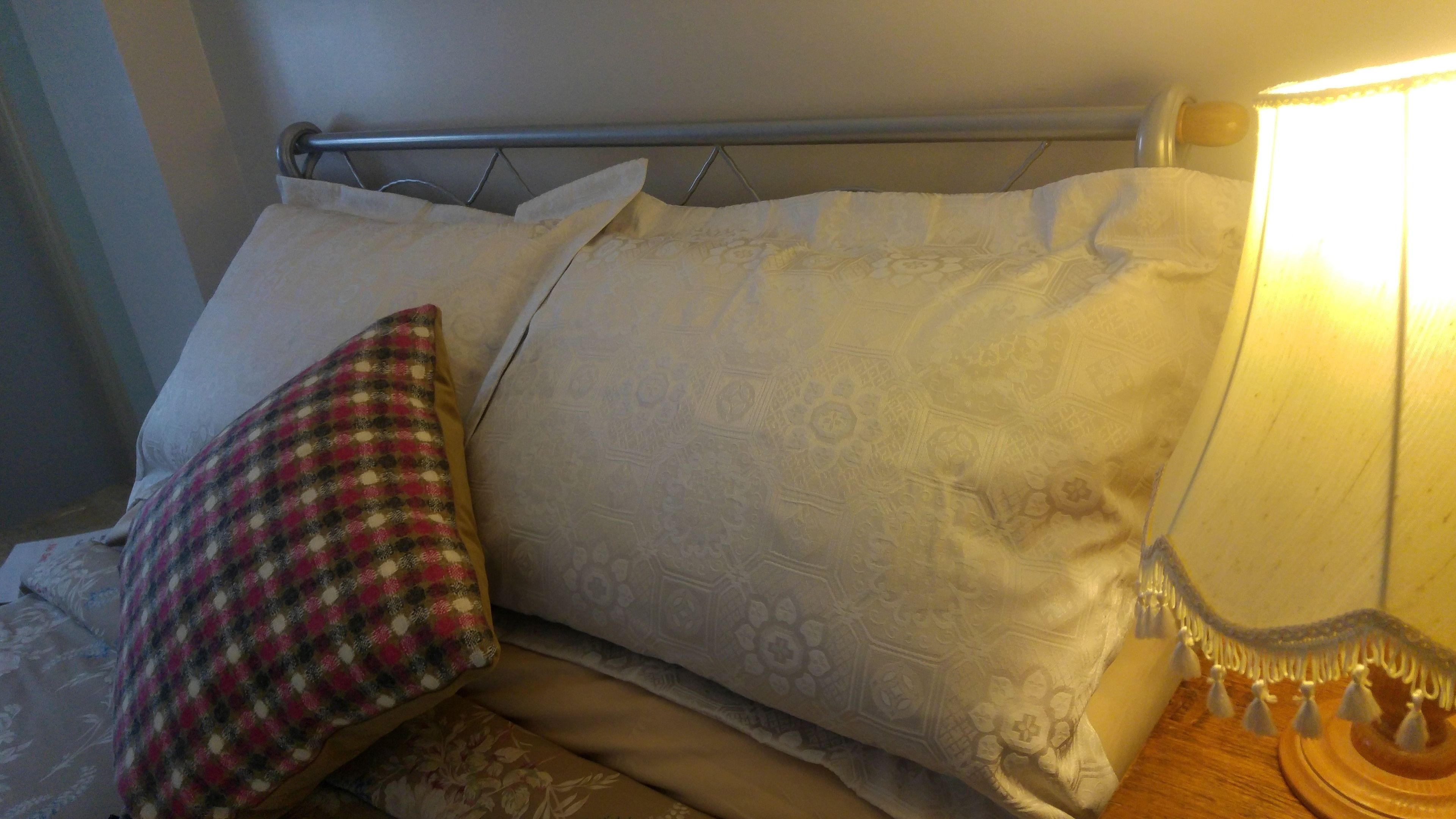 A bed with patterned pillows and a bedside lamp.