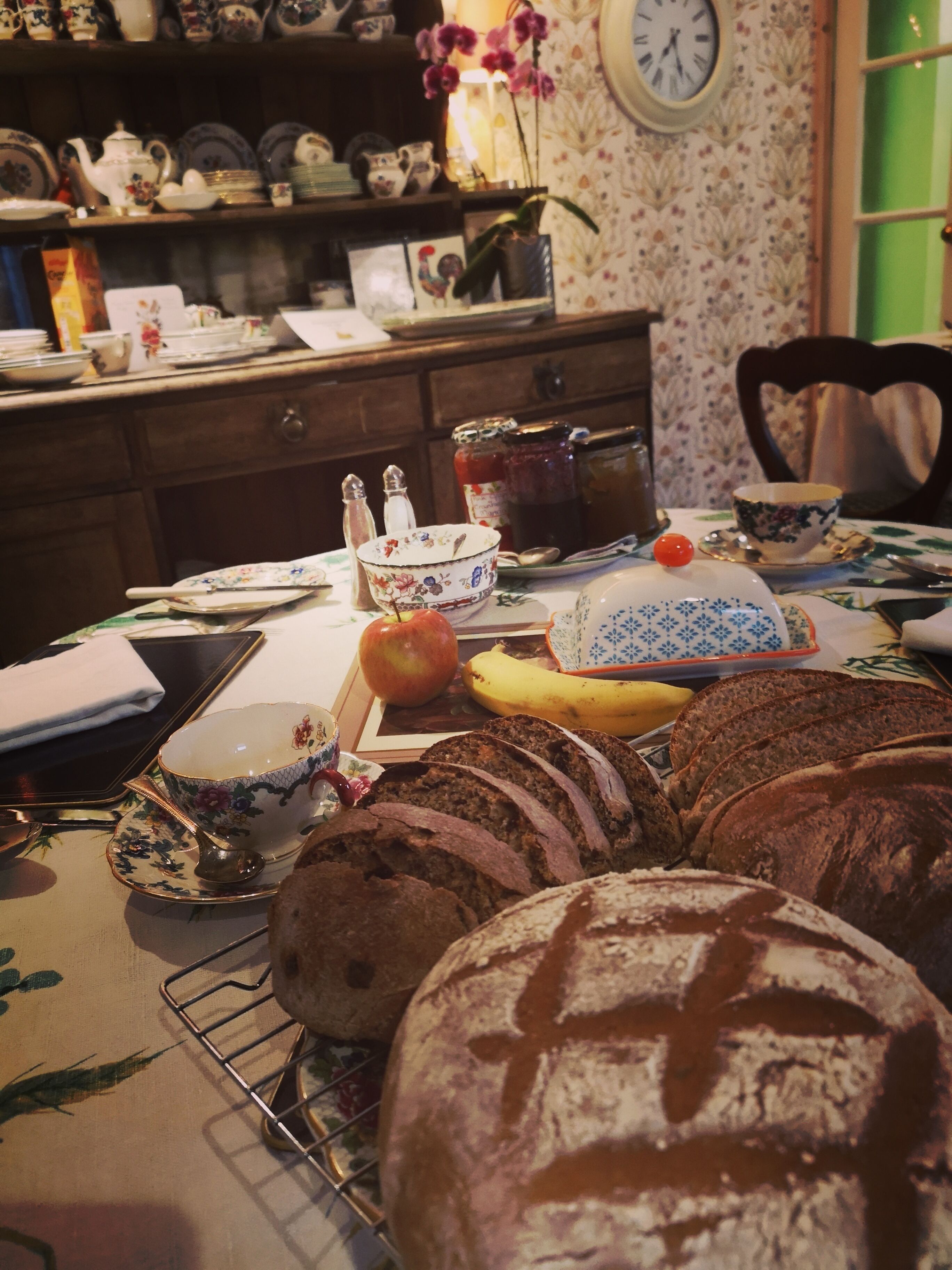 A dining table with various food items and tableware, including bread, an apple, and a banana.