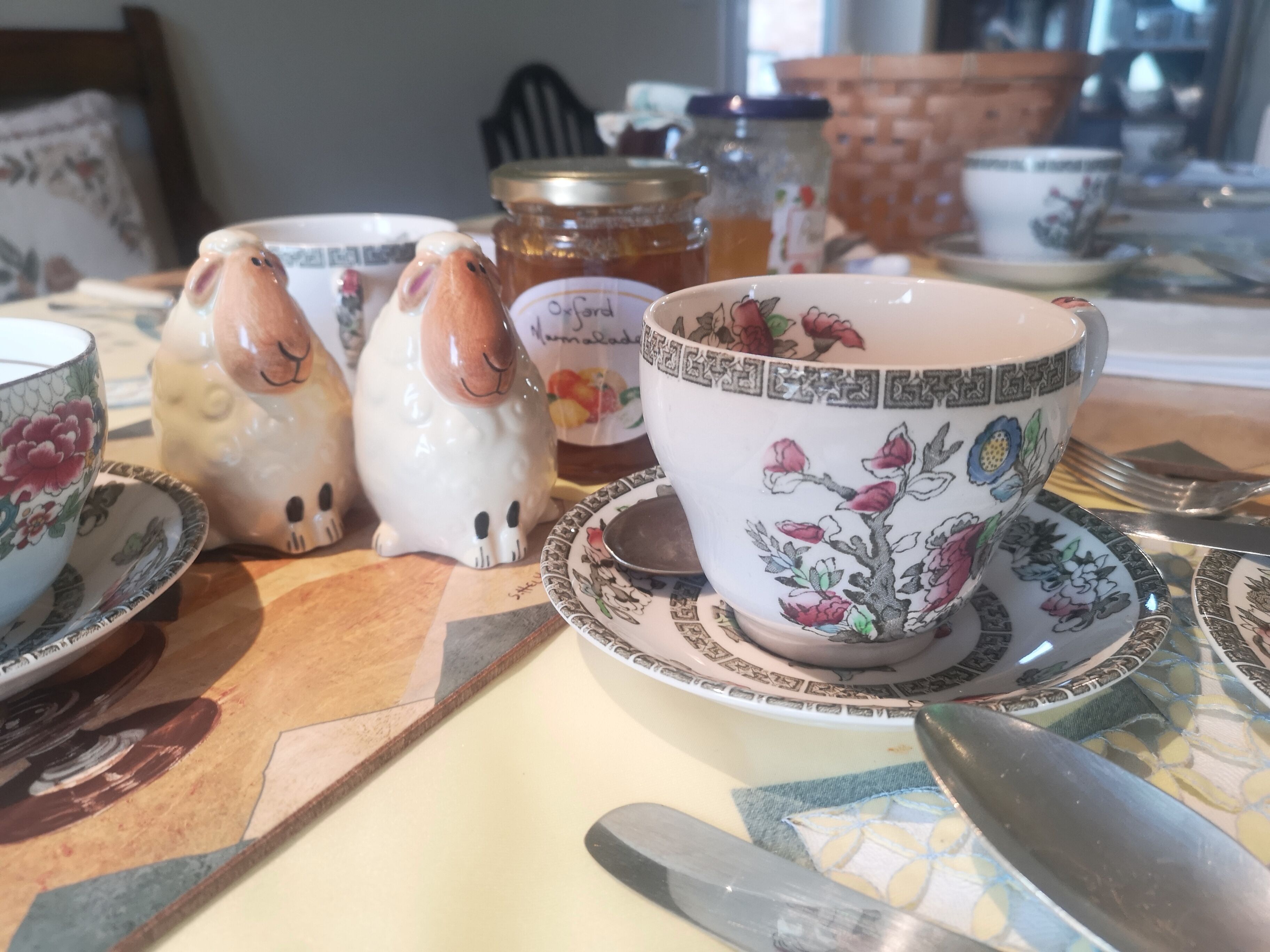 A table with ceramic tea sets, including teapots and cups with floral designs.