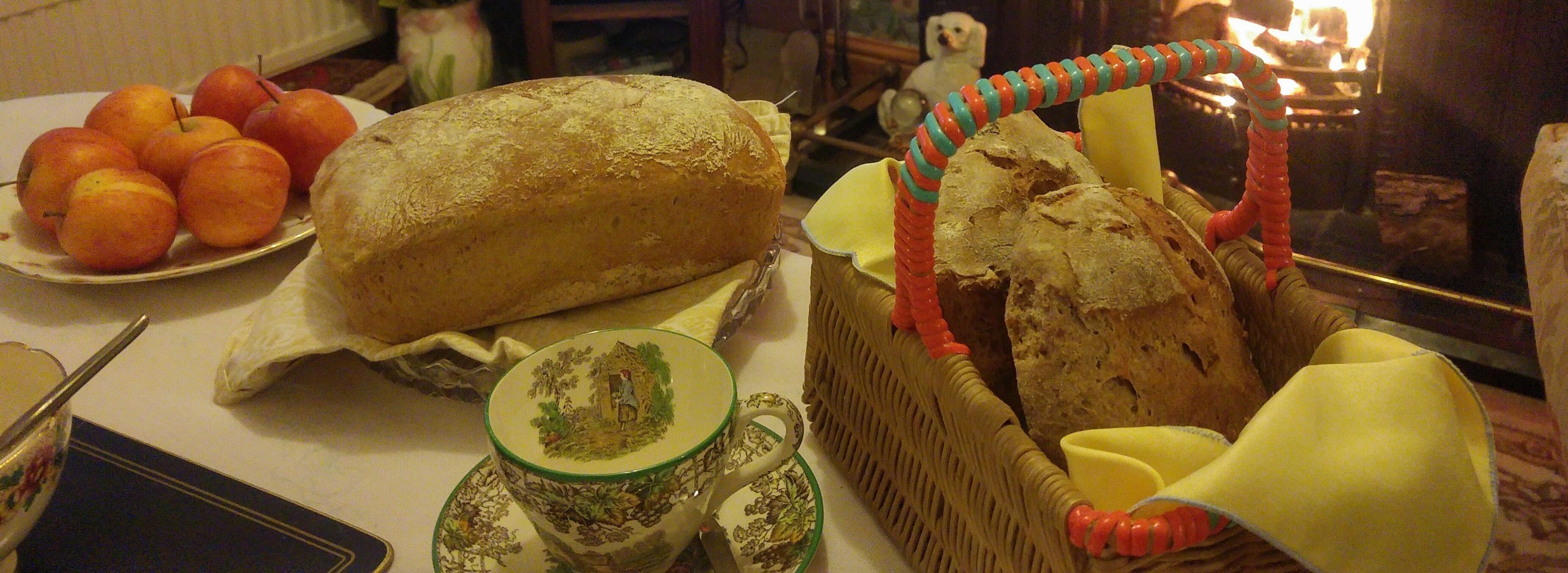 A table with bread, apples, and a basket.