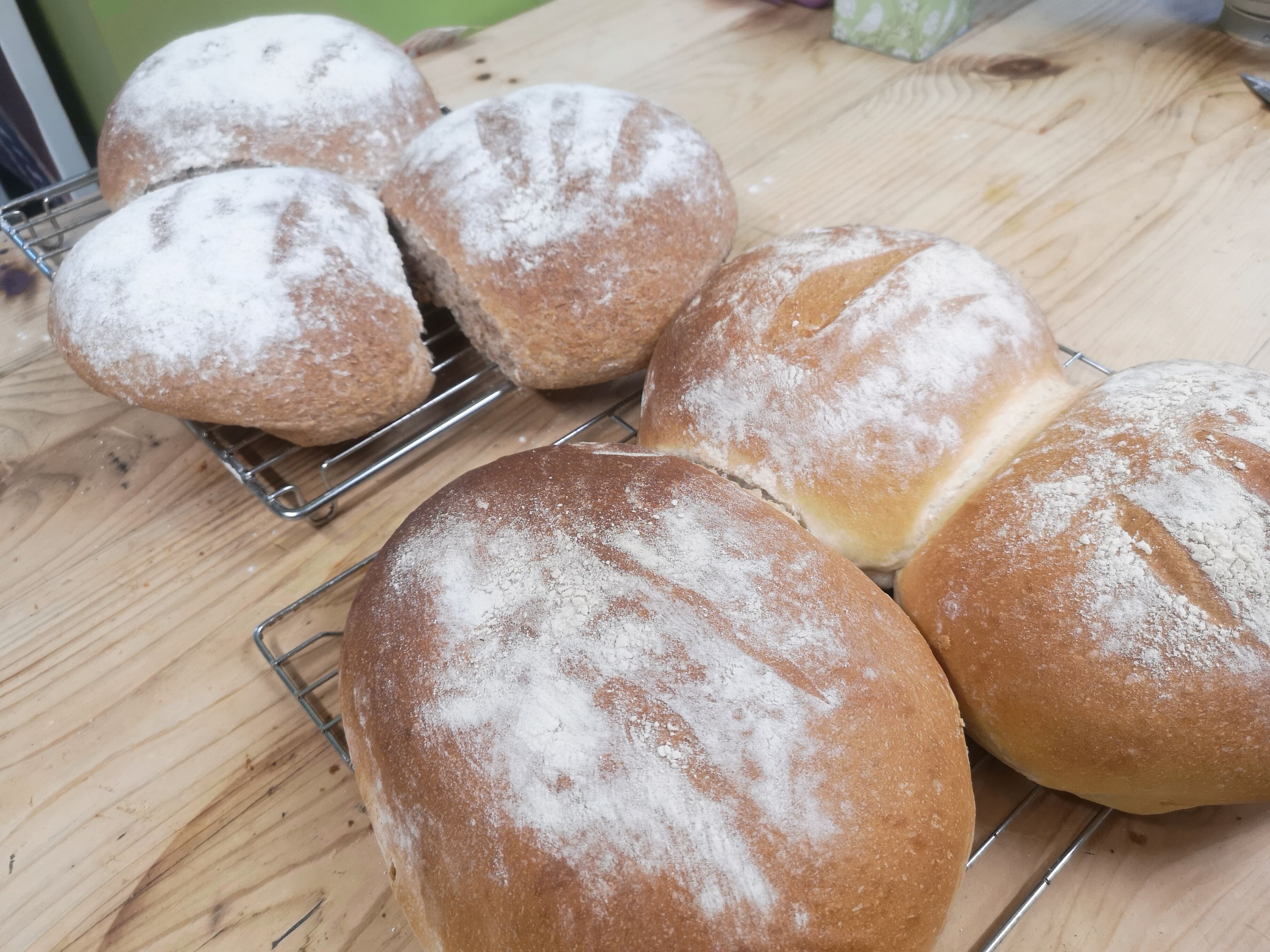 A wooden table with several loaves of bread on cooling racks.