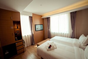 A hotel room with two beds, a wooden wardrobe, a television, and a window with curtains. - Bridal Tea House Hotel Yantai Zhifu (Yantai)