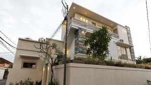 A modern two-story house with a balcony, a small window, and a paved driveway. - Green Studio Apartment Sanur (Denpasar)