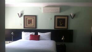 A hotel room with a large bed, two bedside lamps, a nightstand, and two framed pictures on the wall. - Exec Closets Hotel (Gaborone)
